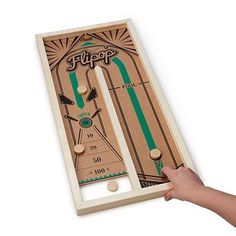 a person holding up a wooden board with an image of a pinball game on it