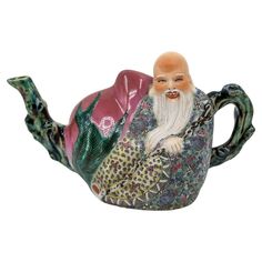 a ceramic figurine of a man sitting on top of a teapot