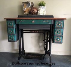 an antique sewing machine table with drawers and knobs on it's legs, painted in teal green