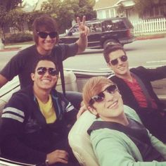 four people sitting in the back of a car with one person giving the peace sign