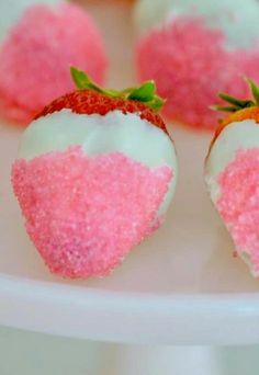 there are strawberries with pink and white frosting on them sitting on a plate