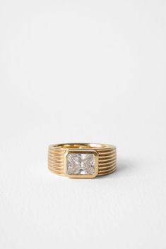 a gold ring with a princess cut diamond in the center, on a white background