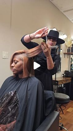 a woman is getting her hair cut at the barbershop with another person in the background