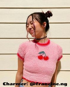 a woman wearing a pink shirt with cherries on her chest and tongue hanging out