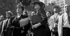 a group of people standing around each other in front of a traffic light on a city street