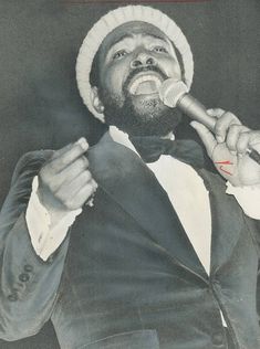 a man in a tuxedo holding a microphone up to his mouth while singing