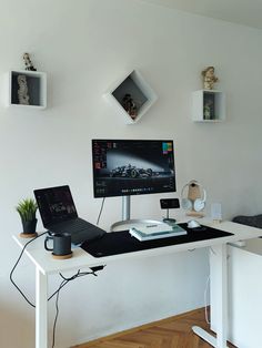 a computer desk with a laptop on top of it next to a plant and other items