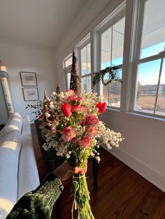 a vase filled with flowers sitting on top of a wooden table next to a window