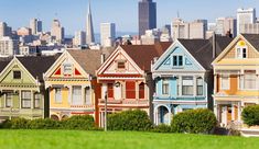 a row of painted houses in front of a city skyline