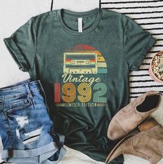 a green shirt with the words vintage 982 on it next to jeans and shoes