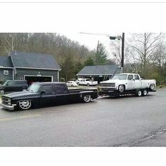 an old truck pulling a classic car on the back of it's flatbed