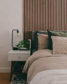 a bed with pillows and blankets on top of it next to a wooden headboard