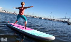 a woman standing on top of a surfboard in the water with her arms outstretched