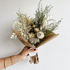 a person holding a bouquet of flowers in their hand with a tag attached to it