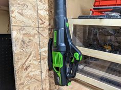 a green and black blow dryer hanging on the wall