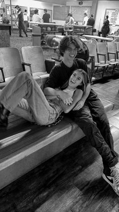 black and white photograph of two people sitting on a bench in an airport with their arms around each other