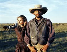 a man and woman standing next to each other in a field