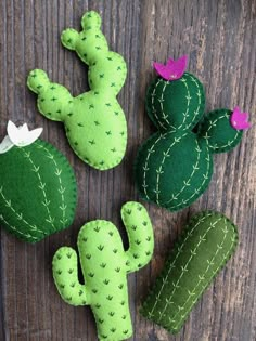 three felt cactus plants sitting on top of a wooden table next to two small succulents