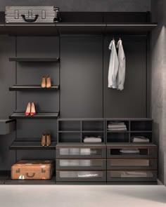 an empty closet with clothes and shoes on shelves next to a suit case in the corner