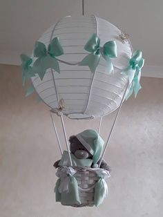 a teddy bear in a hot air balloon with bows hanging from it's side