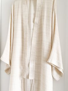 Elevate your lounge wear style with the Ivory Smooth Textured Turkish Cotton Kimono, woven with a beautifully intricate pattern that feels incredibly soft against the skin. Crafted from 100% Turkish Cotton, it ensures both comfort and style for your moments of relaxation at home. Available in one size. Color: Ivory. Material: 100% Cotton. Made in Turkey. Unisex one size. Machine wash delicate. Tumble Dry low. Elegant Long Sleeve Relaxed Fit Kimono, White Spring Kimono For Relaxation, Elegant Cotton Kimono, Elegant Beige Kimono For Loungewear, Cream Long Sleeve Kimono For Loungewear, Elegant Cream Kimono For Loungewear, Cream Kimono For Spring Loungewear, Beige Relaxed Fit Kimono For Loungewear, Spring Cream Kimono For Loungewear