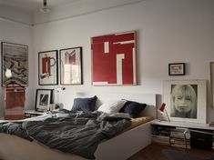 a bed sitting in a bedroom next to a wall with pictures hanging on the walls