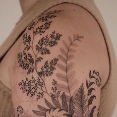 a woman's arm with flowers and leaves tattooed on the back of her shoulder