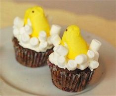 two cupcakes decorated with marshmallows are sitting on a plate