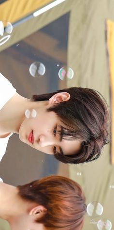 two young women standing next to each other in front of bubbles on a glass surface