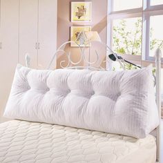 a white bed in a bedroom next to a window