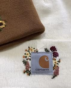 a close up of a patch on a sweater with flowers and leaves around the patches