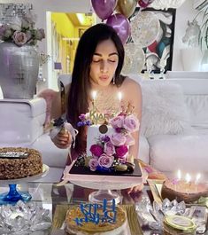 a woman sitting in front of a cake with candles on it