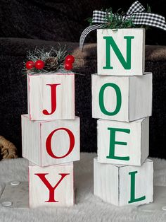 two wooden blocks with the word noel spelled out in red, green and white letters