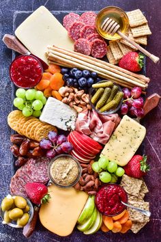 an assortment of cheeses, crackers, fruit and nuts on a platter