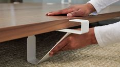 a person's hand is on the edge of a wooden table with white handles