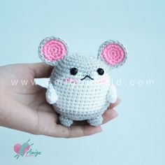 a hand holding a small crocheted toy with ears on it's head