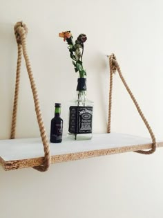 a shelf with two bottles and flowers on it, hanging from the wall next to each other