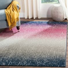 a living room area with a blue couch and pink rug on the floor next to a window