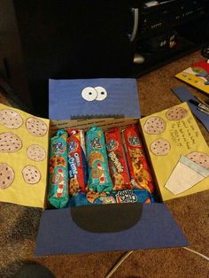 an open box with cookies and crackers in it on the floor next to a tv