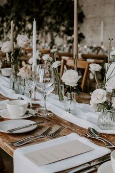 the table is set with white flowers and place settings for two people to sit at