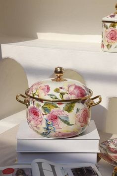 a pot with flowers painted on it sitting on top of a stack of books