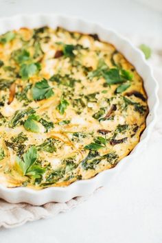 a quiche with spinach and cheese in a white dish