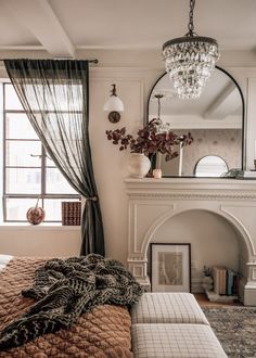 a bedroom with a bed, fireplace and mirror on the wall in front of it