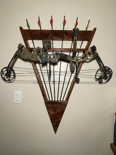 a wall mounted archery bow rack with arrows and other things on it's side