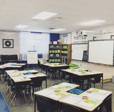 an empty classroom with desks and whiteboards on the wall in front of it