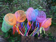 there are many different colored plastic objects in the basket on the ground near some bushes