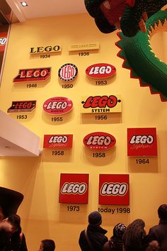 a wall with legos and logos on it in front of a group of people