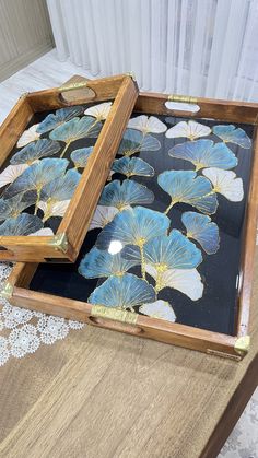 two wooden trays sitting on top of a table covered in blue and white flowers