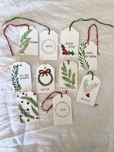 christmas tags with holly and mist on them are laid out on a sheet of white paper