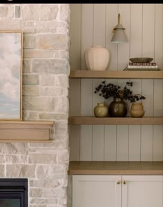 shelves with vases and other items on them in front of a fire place next to a brick wall